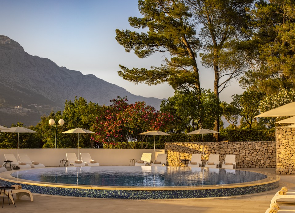 Warm light and glow of a sunset light over a sea water outdoor pool at Aminess Younique Liburna Hotel.