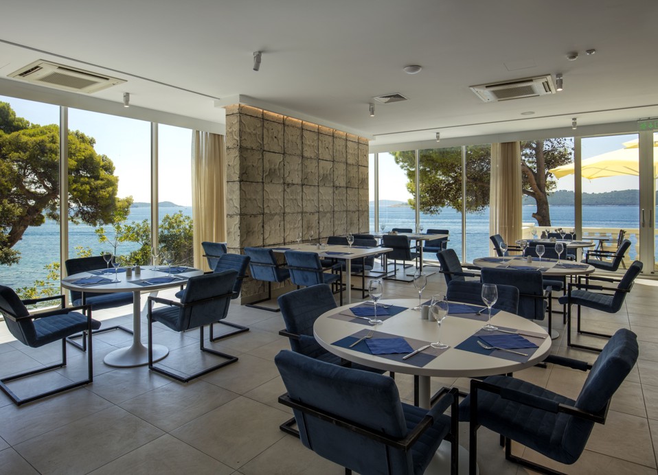 Interior view of the buffet restaurant at Aminess Bellevue Hotel featuring floor to celling windows overlooking sea view.