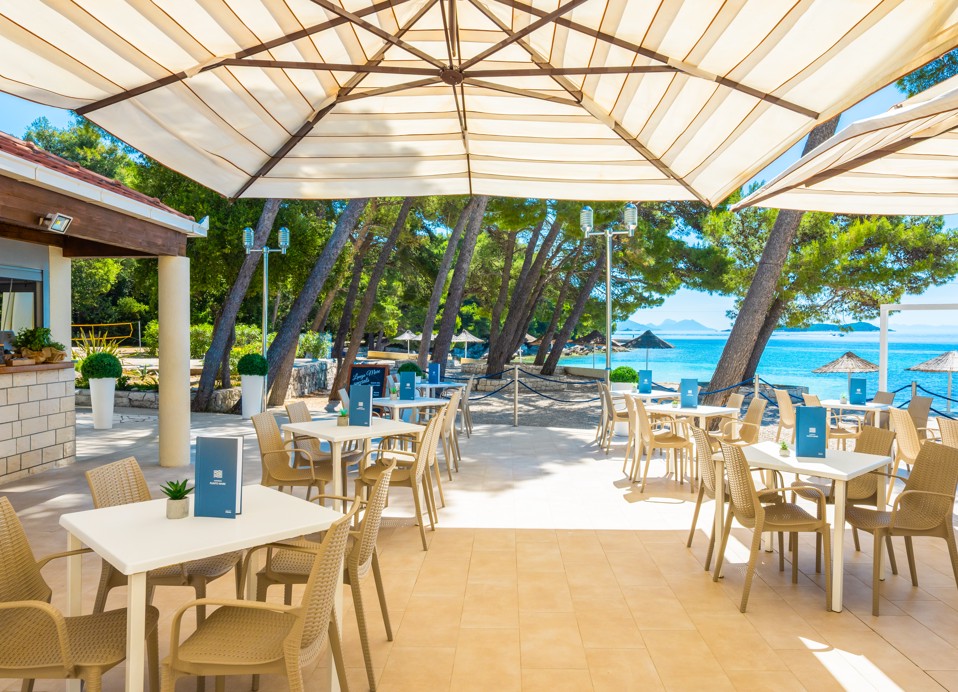 Terrasse der Bar und des Restaurants mit Blick auf den Strand und die Bäume im Aminess Vival Grand Azur Hotel.