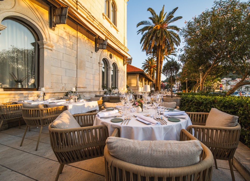Lussuosa cena all'aperto al tramonto sulla terrazza del ristorante 7 Seas a Korcula, che mette in mostra raffinate impostazioni di tavoli da pranzo con bicchieri da vino.