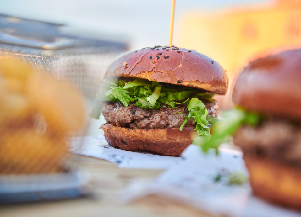 Sočen gurmanski burger, postrežen s hrustljavim pomfritom in svežo zelenjavo v bližini Aminess Style Camping Atea Resort.