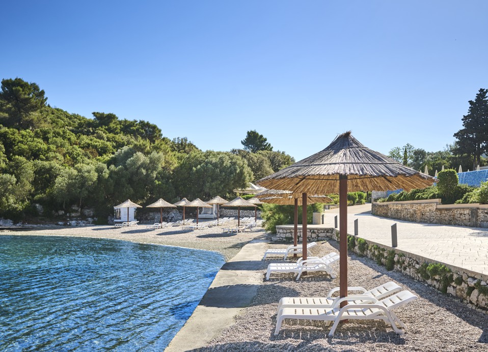 Sonnenliegen am Kieselstrand, mit atemberaubendem Blick auf das Meer bei Aminess Vival Port9 Residence.