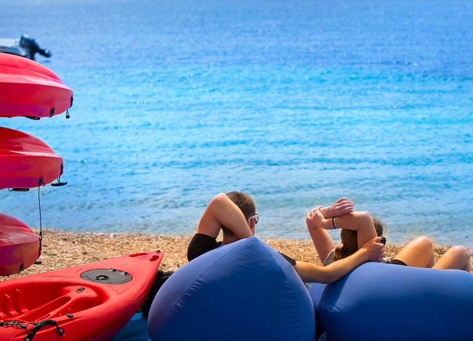 Koppel ontspant op het strand naast een kajak bij Aminess Planet Camping Maravea Resort, Novigrad Kroatië