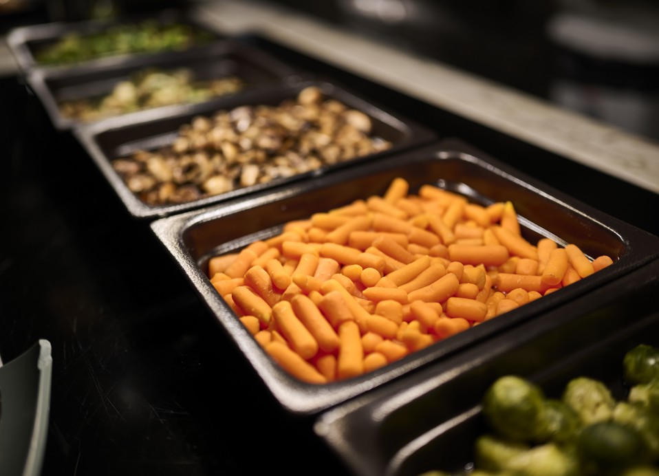 Warme groentegerechten zoals wortelen en champignons op het hotelbuffet