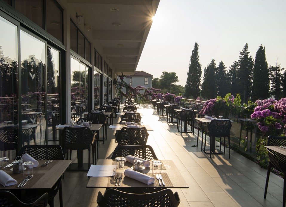 Terasa restavracije Oliveto v Aminess Vival Velaris Resortu na otoku Brač s pogledom na vrt in sončni zahod.