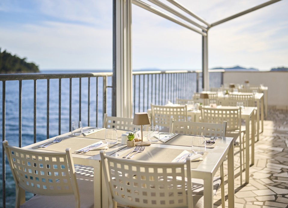 Moderne und elegante weiße Tischdekoration auf der Terrasse mit Meerblick im Aminess Younique Lume Hotel.