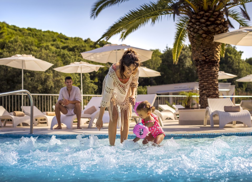 Elternteil und Kind genießen den Urlaub am Infinity-Pool im Aminess Vival Port9 Resort in Korcula.