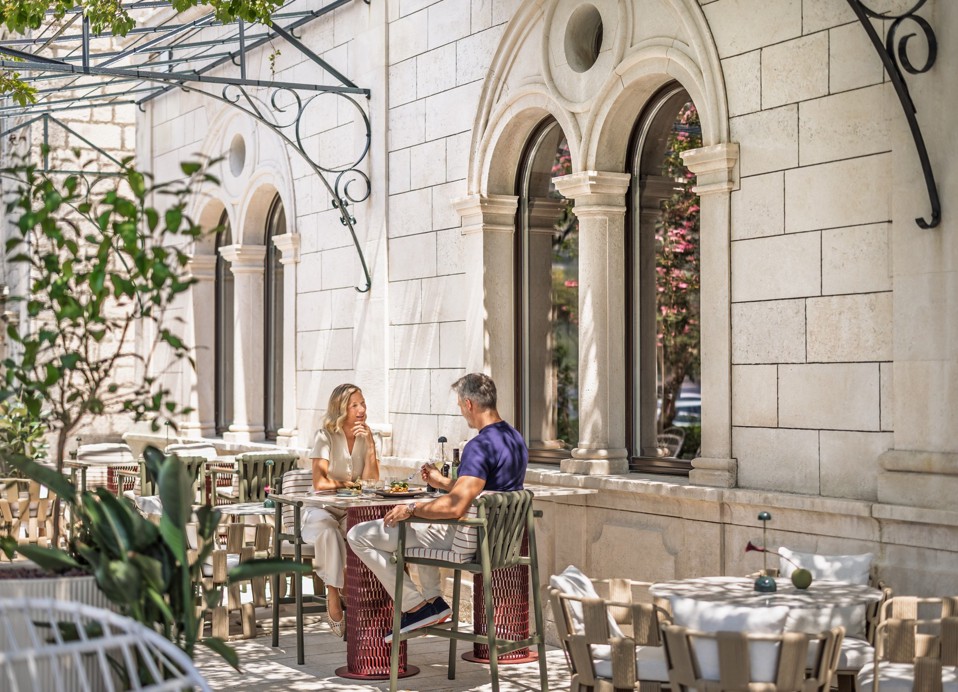 Una coppia cena sulla terrazza dell'Aminess Younique Korcula Heritage Hotel accanto alla facciata.