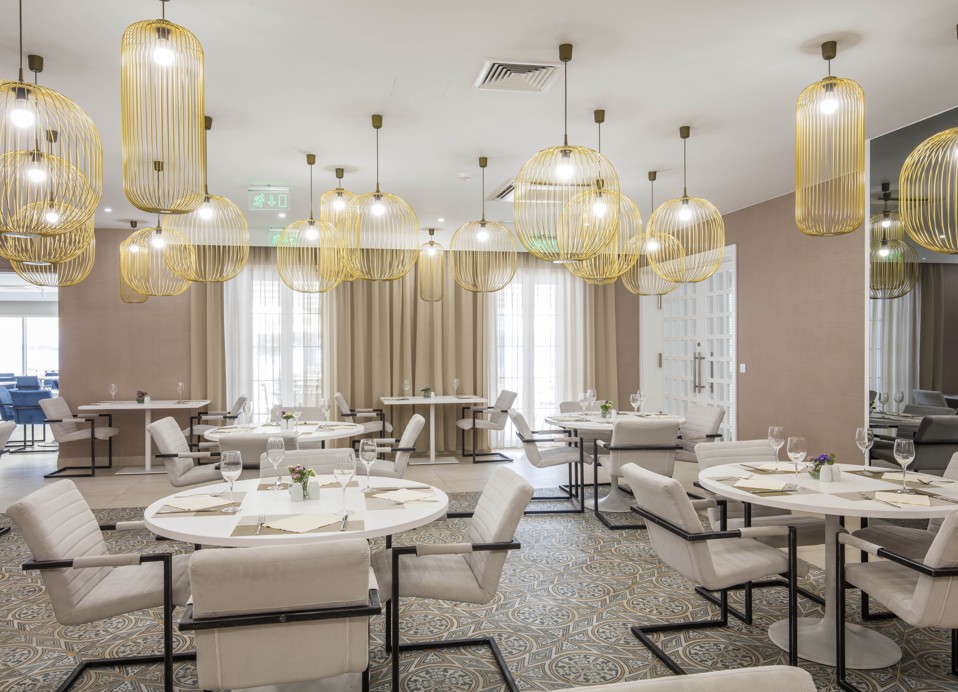 Elegantna notranjost restavracije bližnjega hotela, ki se ponaša z moderno dekoracijo, dekorativno razsvetljavo in stilsko vzdušje, odprto za goste Aminess Maradiso Bellevue Village.