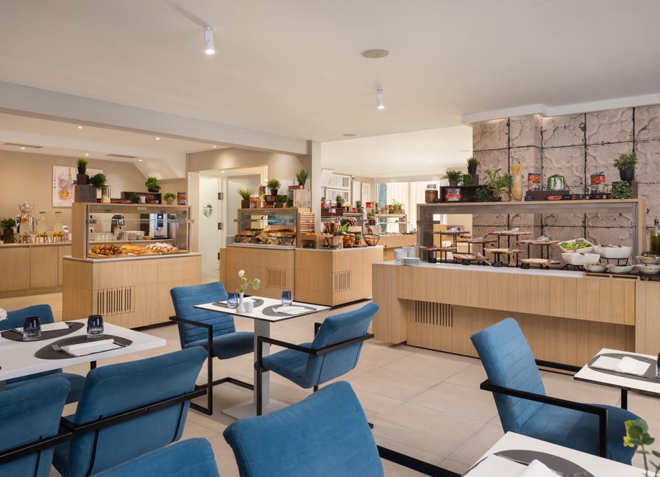 Buffet restaurant at Younique Bellevue Hotel by Aminess with blue chairs and set tables.