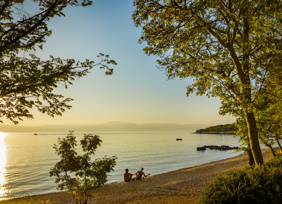 Zlatni zalazak sunca nad plažom s obrisima drveća, stvarajući mirnu atmosferu u Aminess Style Camping Atea Resort holiday home.
