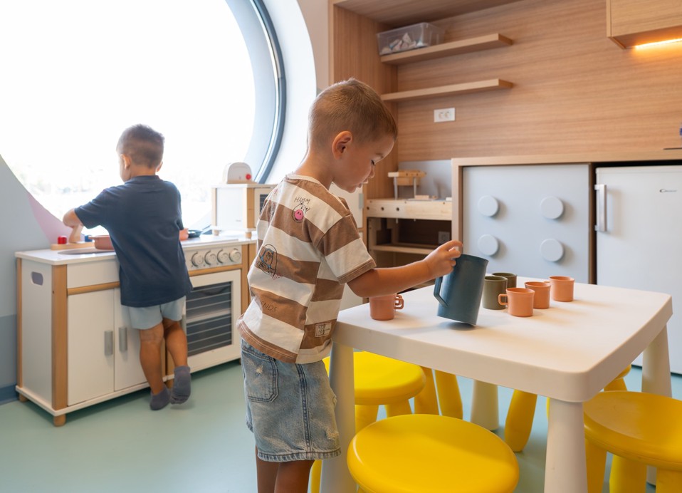 Due bambini giocano nella cucina giocattolo nella sala giochi dell Aminess Khalani Hotel.
