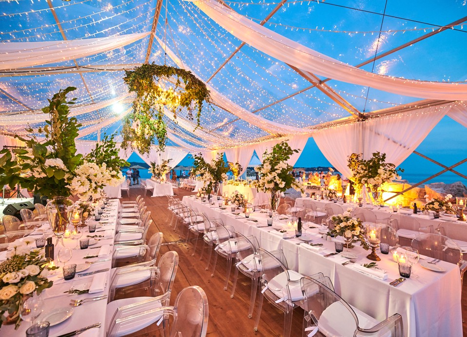 Romantic night ambiance in a tent illuminated by fairy lights, with a view of the sea in the background.