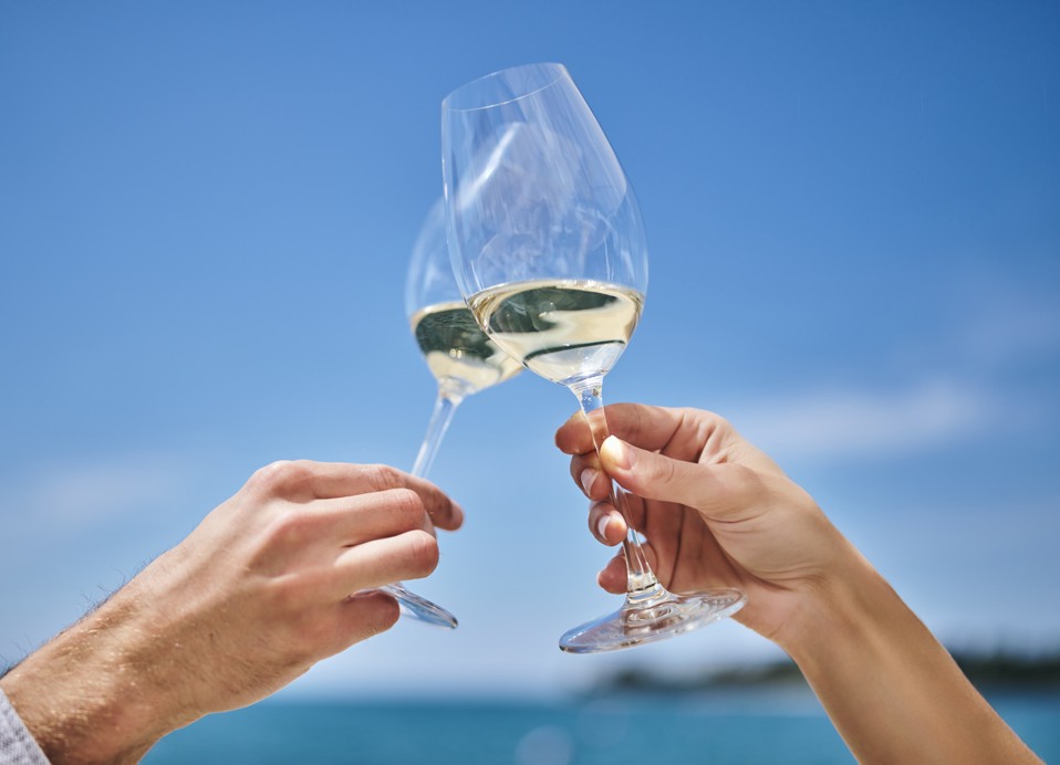 Proosten met een glas witte wijn aan zee bij restaurant Half 8