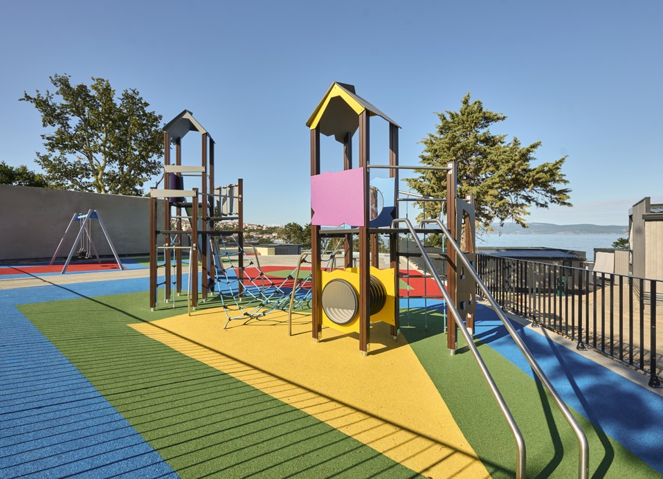 Kinder klettern und erkunden eine farbenfrohe Outdoor-Aktivitätszone unter der Anleitung von Animateuren im Aminess Style Camping Atea Resort.