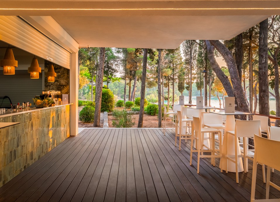 Terasni prostor restavracije in bara Punto Mare v letovišču Aminess Vival Velaris na Braču, obdan z borovci ob morju