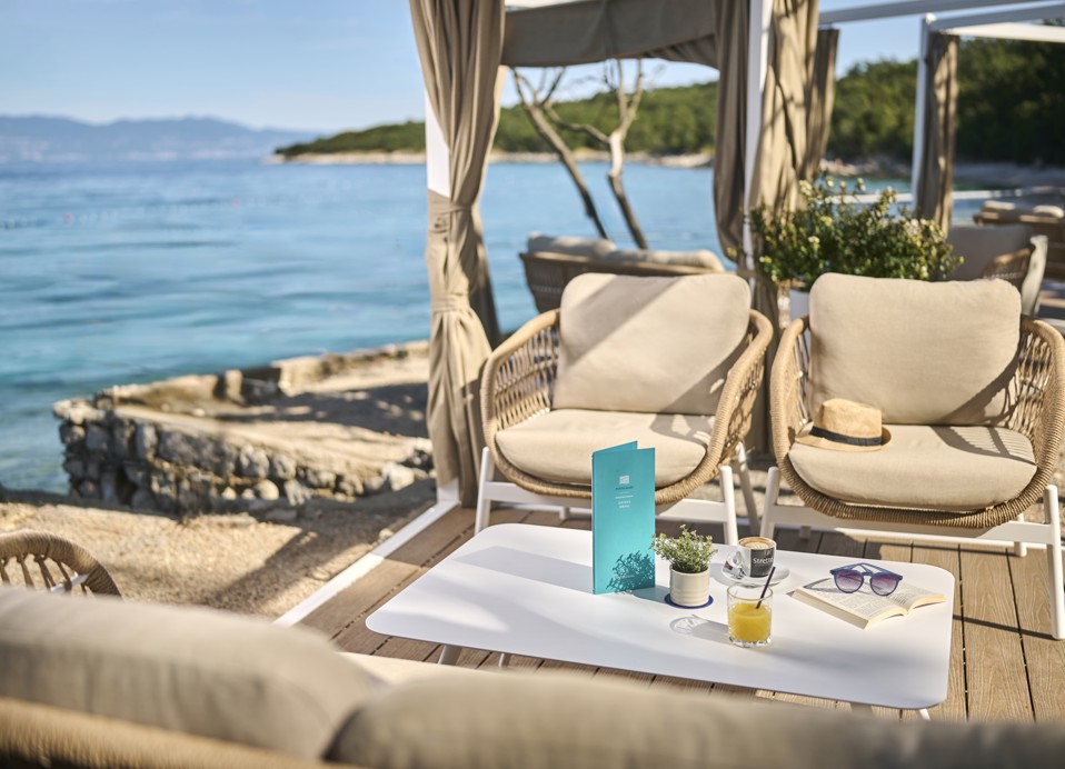 Close-up of a lounge bar table at Punto Mare with drinks, a book and sea view