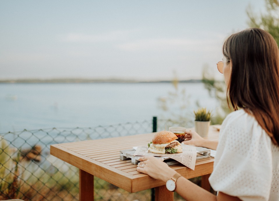 Lady eating a cheeseburger from the Oleandar bar at Aminess Planet Camping Sirena, Novigrad, Croatia