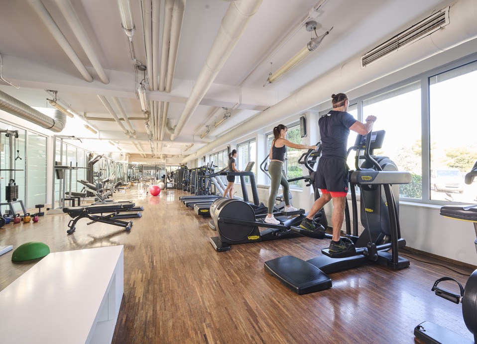 Moderne fitnessruimte met grote ramen en trainingsapparatuur in het Aminess Maestral Hotel in Novigrad