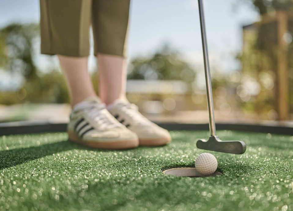 Mini golf player putting the ball towards the hole