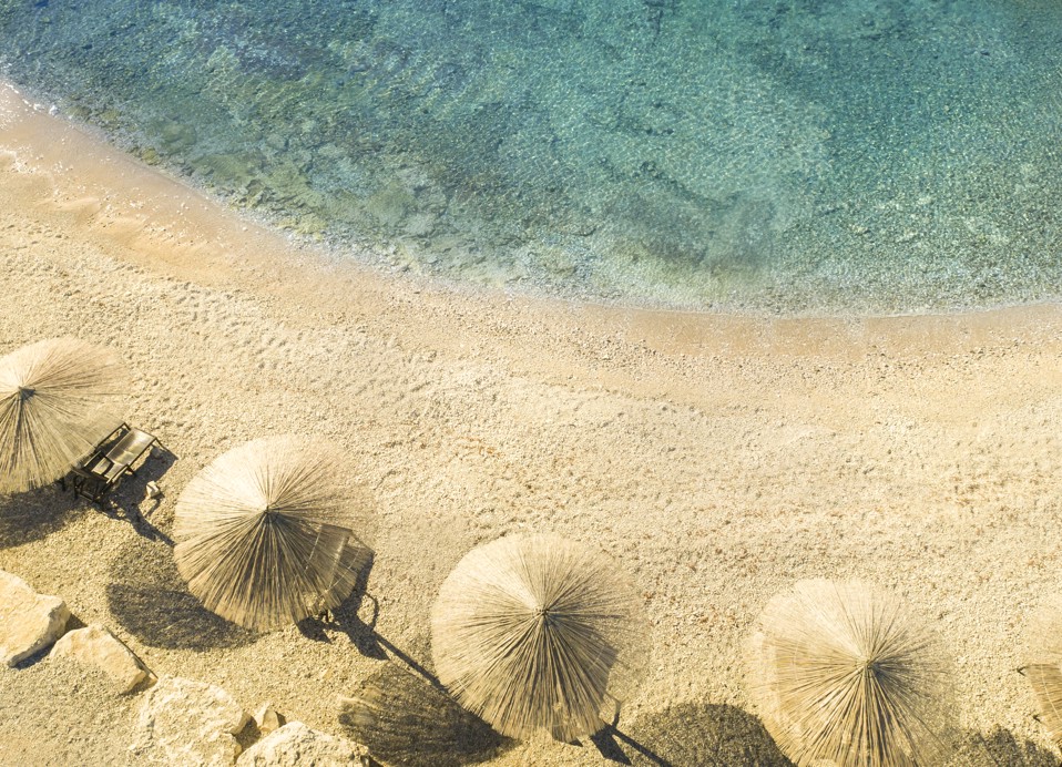 Pogled na Punto Mare Fun & Beach zonu s ležaljkama, suncobranima, kabanama, barom, infinity bazenom i morem.