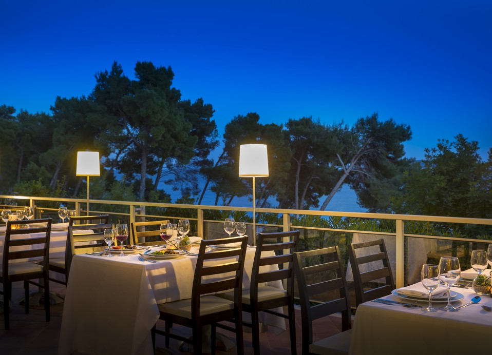 Candlelit-Dinner-Arrangement auf einer Terrasse unter dem Abendhimmel mit Blick auf den Wald im Aminess Vival Grand Azur Hotel.