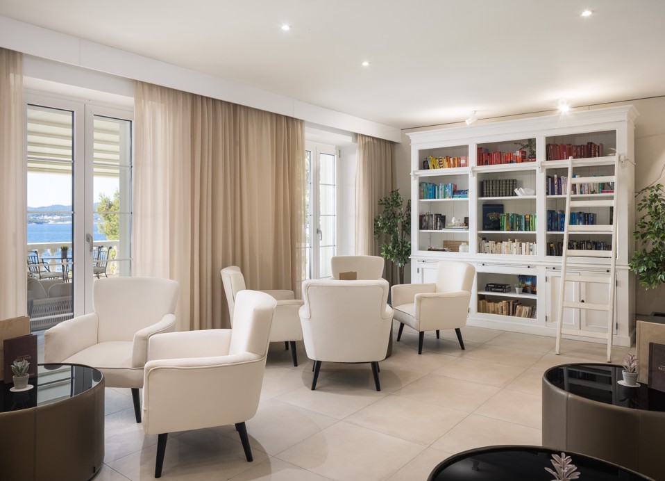 Bar Noir lounge at Younique Bellevue Hotel by Aminess with armchairs and a bookshelf.