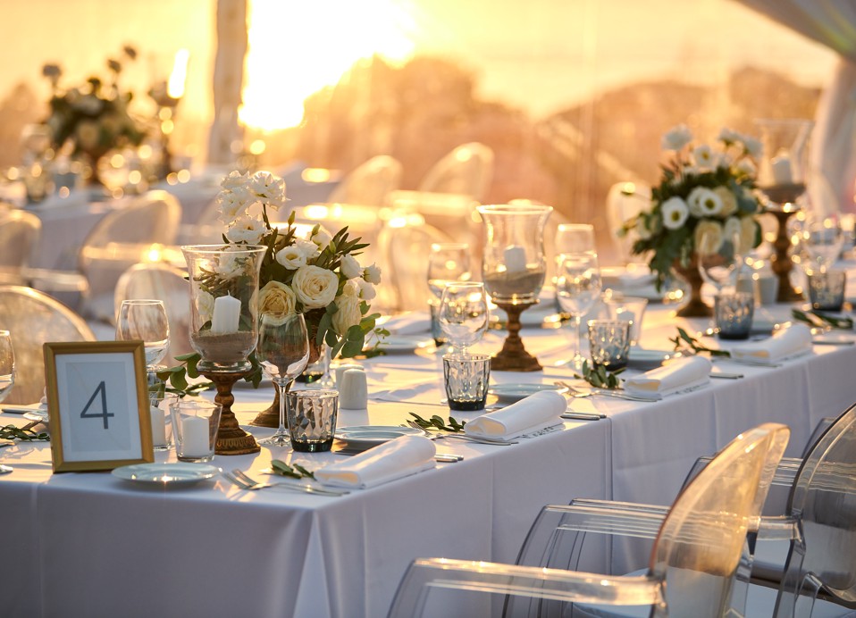 The image shows a wedding table decoration with flowers and table number signage.