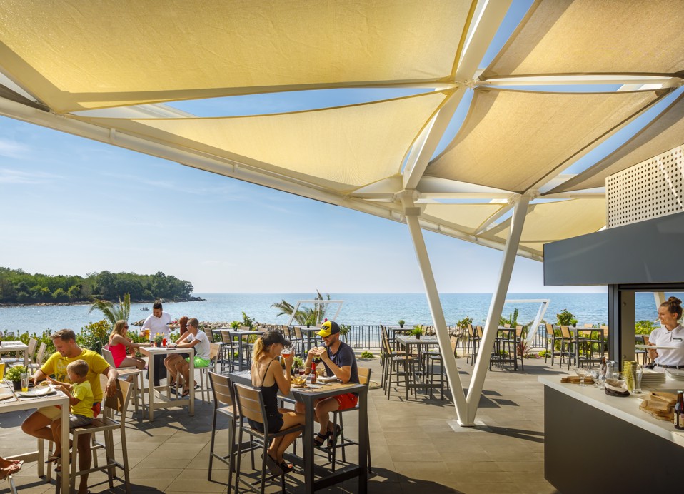 Gäste genießen ihre Mahlzeiten in einem Restaurant in der Nähe des Meeres im Aminess Planet Camping Maravea, Novigrad