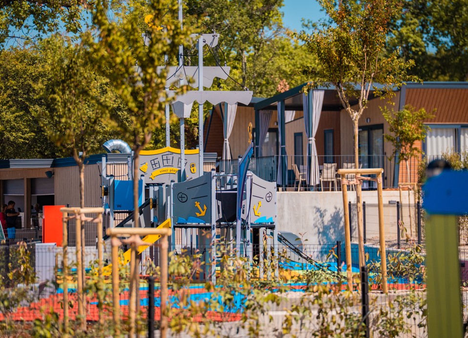 Kinderspielplatz mit Piratenschiff-Thema, umgeben von Grünflächen und Mobilheimen im Aminess Style Camping Atea Resort.