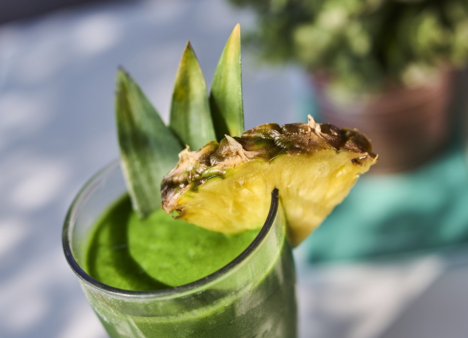 Grüner Smoothie garniert mit einer Scheibe Ananas.