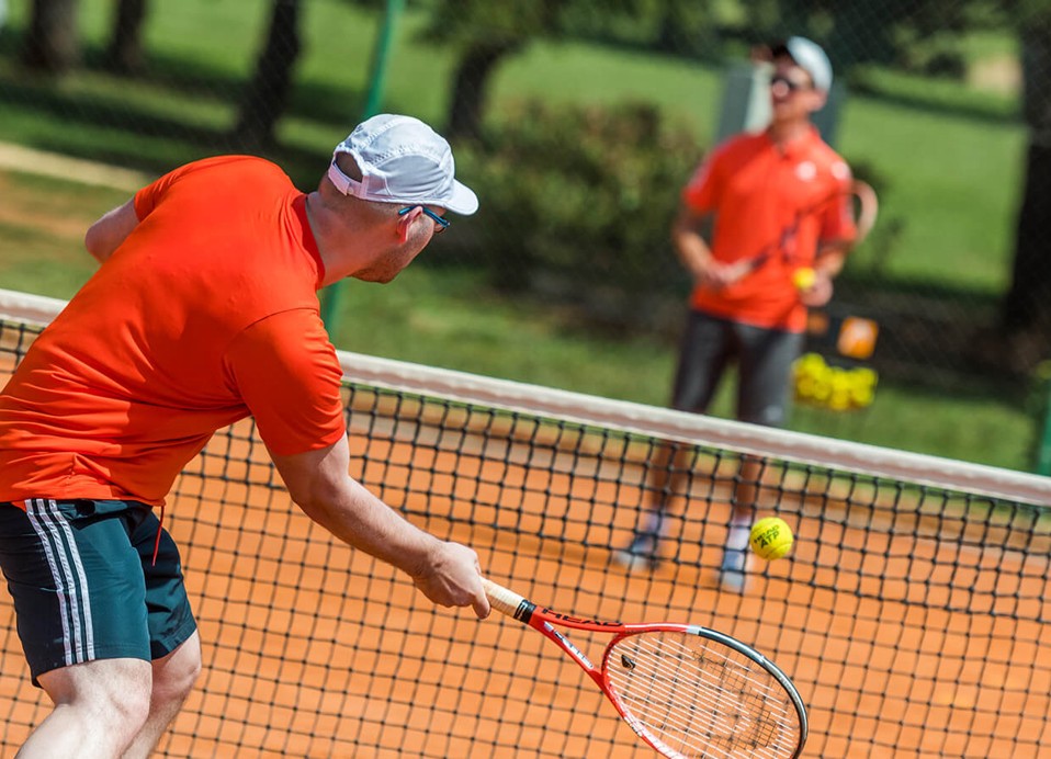 Tennisspieler auf dem Platz im Aminess Planet Camping Sirena in Novigrad, Kroatien, mit üppigem Grün im Hintergrund