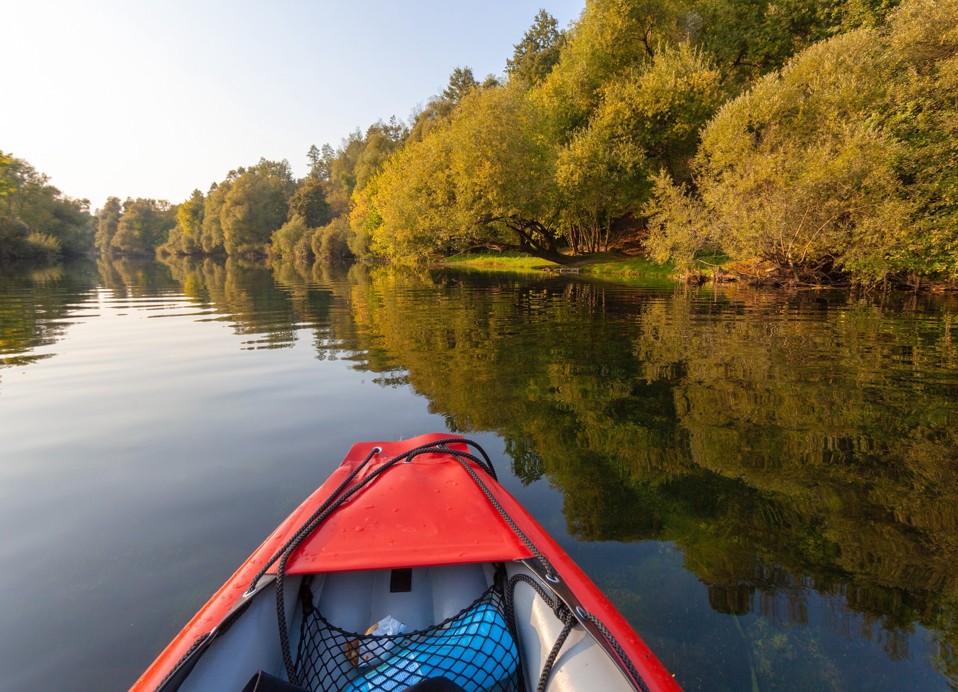 Kayak on the calm Dobra River surrounded by green forest near Karlovac.