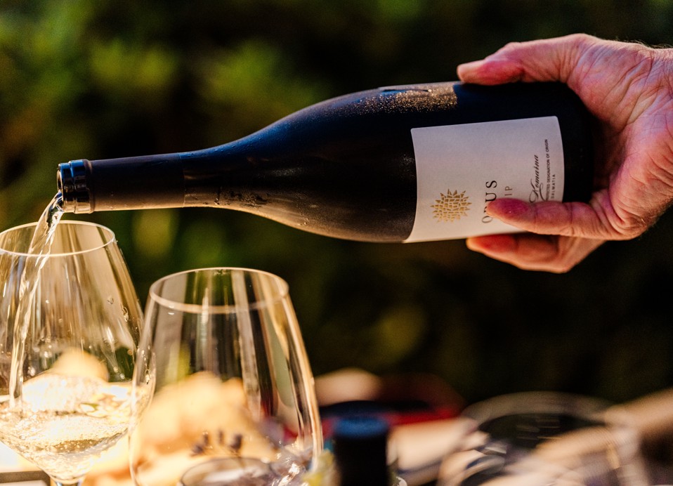 Wino Opus Posip jest nalewane z butelki do kieliszka na zewnątrz.
