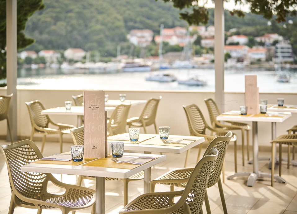 Ein Tisch, gedeckt mit Tellern, Besteck und Gläsern auf der Terrasse, mit einem wunderschönen Blick auf die Umgebung im Aminess Vival Port9 Resort in Korcula.