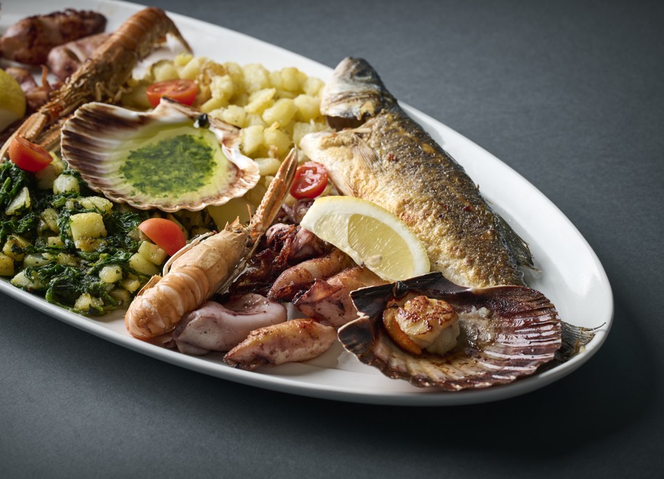 Svež in živahen pladnjič morskih sadežev, ki vključuje pečeno ribo, kozice in pisano zelenjavo v Il Cantuccio blizu Aminess Style Camping Atea Resort.