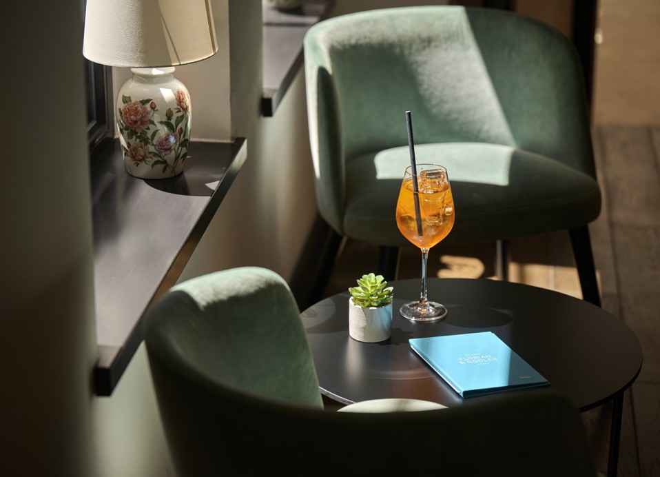 Koktajl obok zielonych foteli w barze lobby Aminess Florian and Godler Hotel.