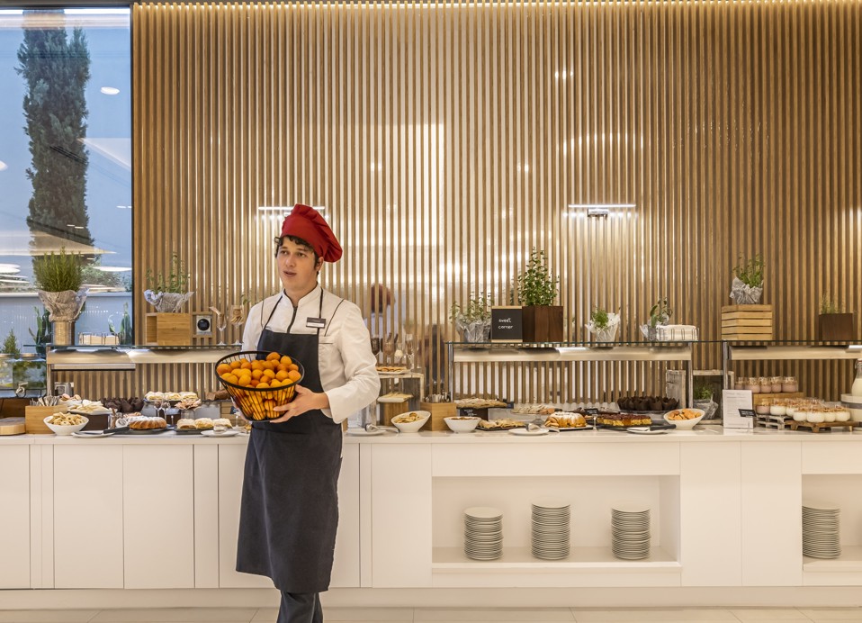 A sweet corner of the biffe with employee carrying a bowl of food at Aminess Laurel Khalani hotel.