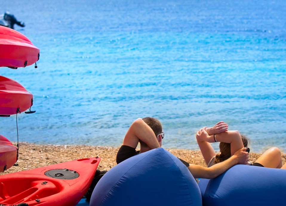 Paar entspannt neben einem Kajak im Aminess Planet Camping Sirena in Novigrad, Kroatien