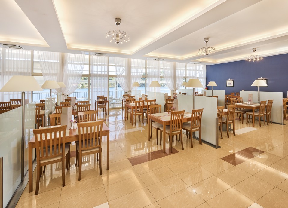 Elegantes Interieur eines Hotelrestaurants mit Holztisch-Sitzgelegenheiten in einer gemütlichen und entspannenden Atmosphäre im Aminess Younique Lume Hotel.