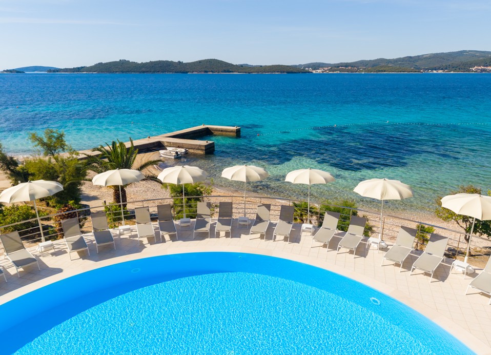 Pool im Orsan Maradiso Hotel by Aminess mit Liegen, Sonnenschirmen und Meerblick.
