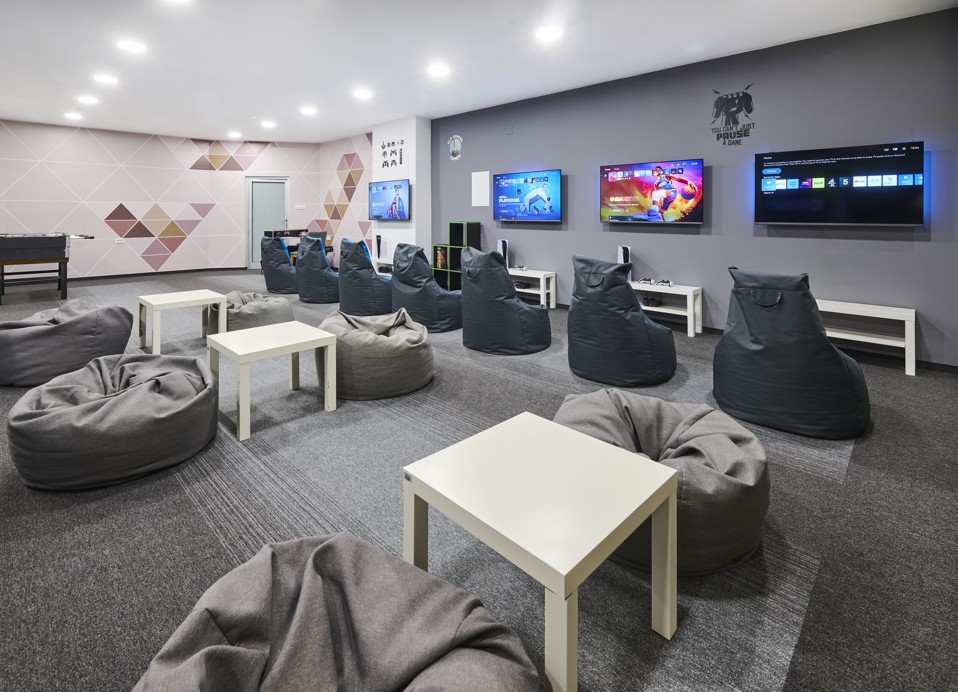 A modern game room with comfortable seating and gaming setups at Magal Maradiso Hotel.