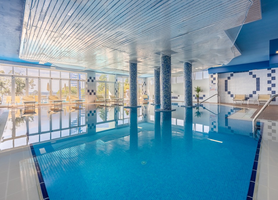 Ampia piscina interna presso l'Hotel Mediteran Maradiso di Aminess con design moderno e grandi finestre.