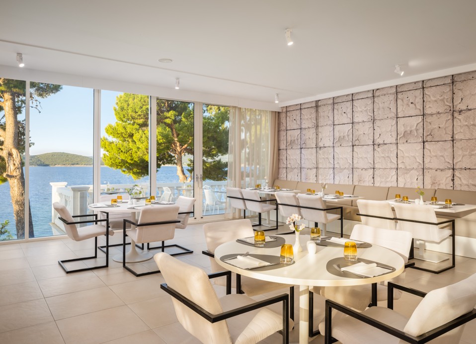 Elegant restaurant at Younique Bellevue Hotel with set tables and a sea view.