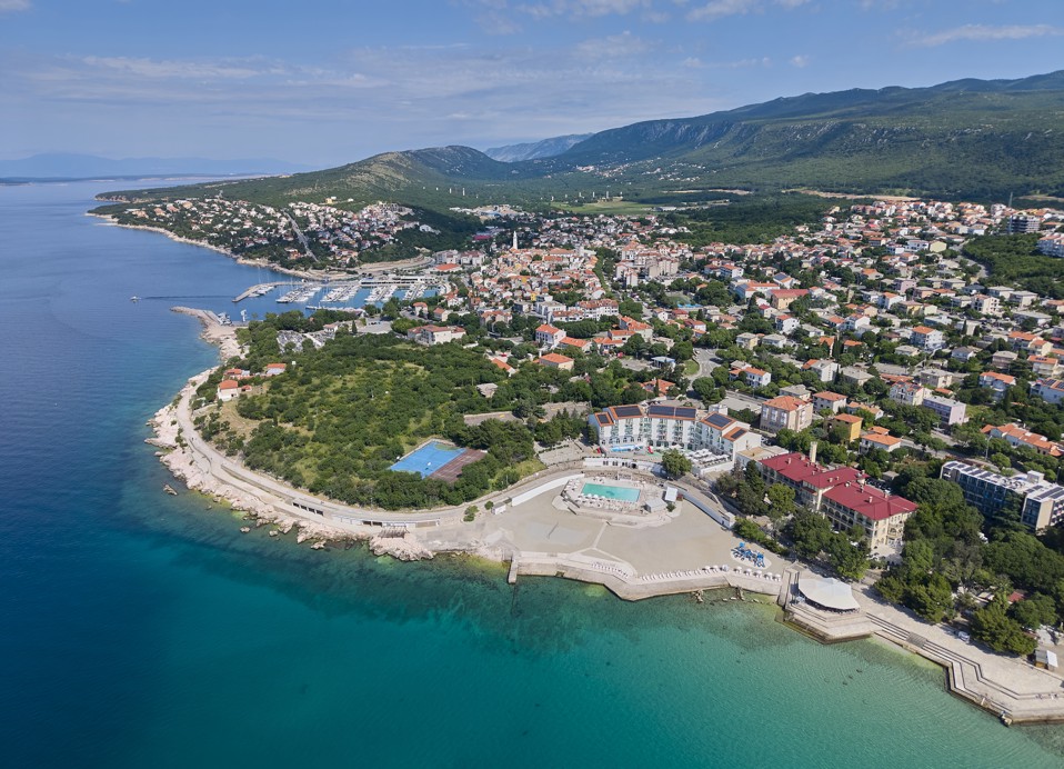 Luftaufnahme von Aminess Vival Lišanj Family Hotels Strand und türkisfarbenem Meer, umgeben von üppigem Grün und der Stadt Novi Vinodolski.