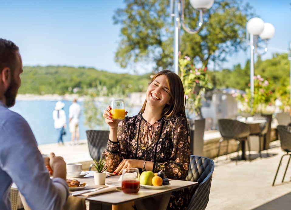 Gosti, ki na sončni terasi Veya Lounge Bara ob Aminess Style Camping Atea Resortu uživajo v prijetni jutranji kavi s pecivom.