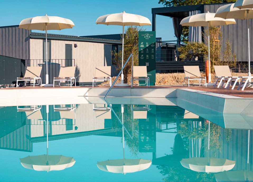 Miran bazen s ležaljkama i suncobranima koji se ogledaju u vodi, u Aminess Style Camping Atea Resortu.