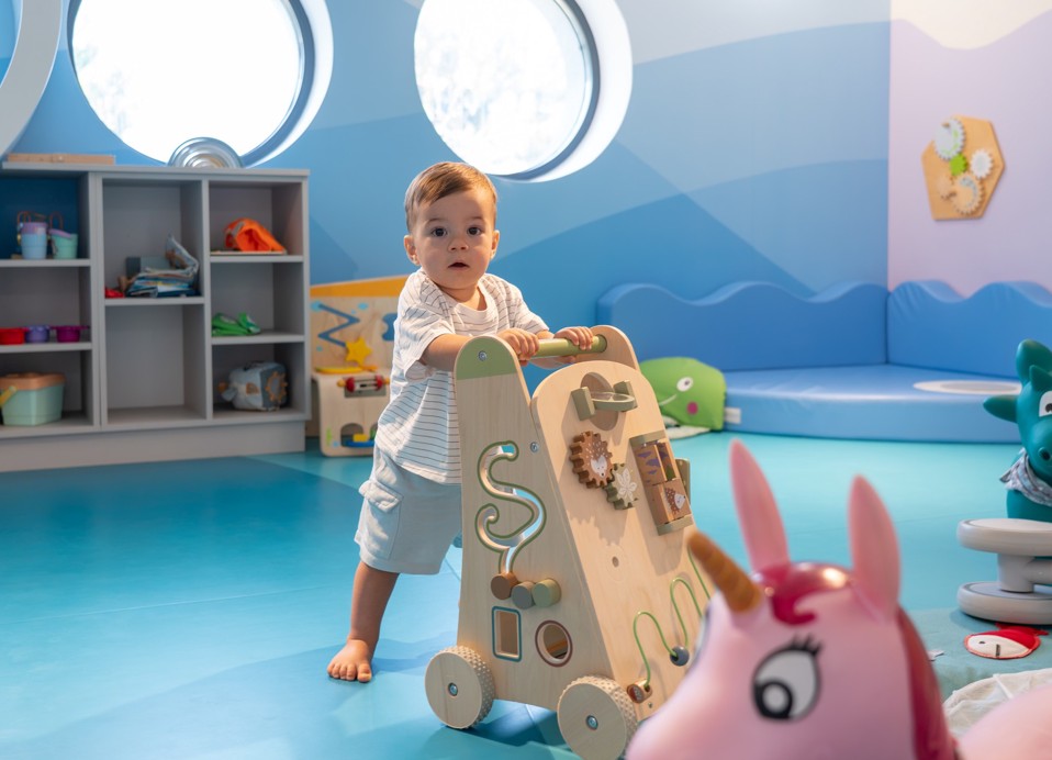 Bambino gioca con un carrellino in legno nella sala giochi dell Aminess Khalani Hotel.