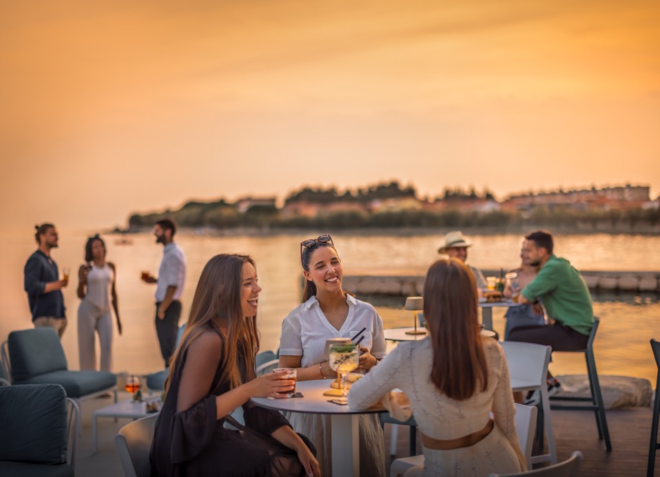 Group of friends enjoying drinks at the infinity pool bar during sunset at Aminess in Novigrad, Istria.
