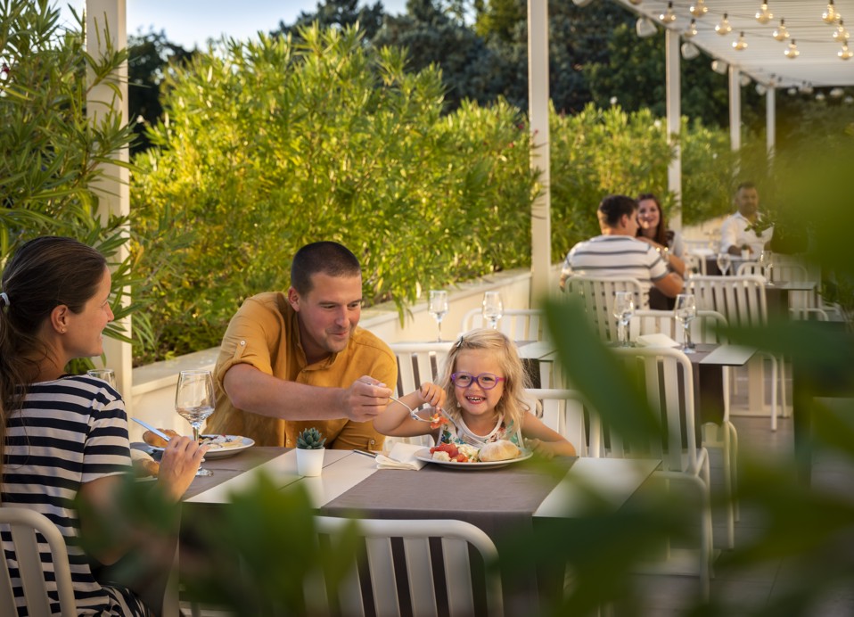 Gezin geniet van een maaltijd in het Magal Maradiso Hotel by Aminess restaurant.